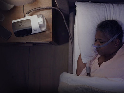 Nainen nukkuu mukavasti ResMedin CPAP-laitteen kanssa